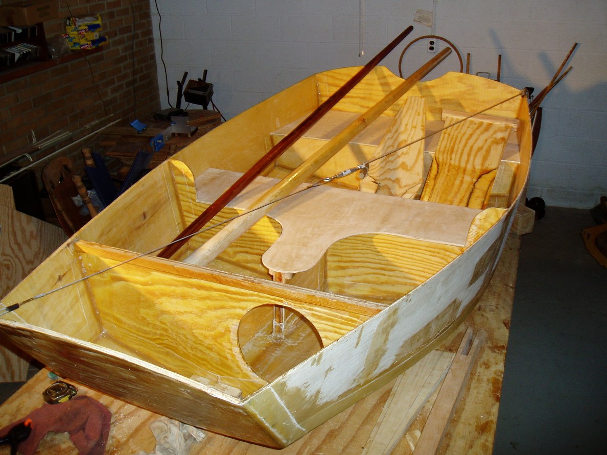 Here's Most of the Pieces
Everything but the front deck. The sprit is redwood for lightness. The mast is hollow and made from 4 staves cut from 2x4's. The hull was about 7/16" out of square so I installed a bridle to try and get it into shape. The rudder and daggerboard were shaped with a block plane. That was a lot of work.
