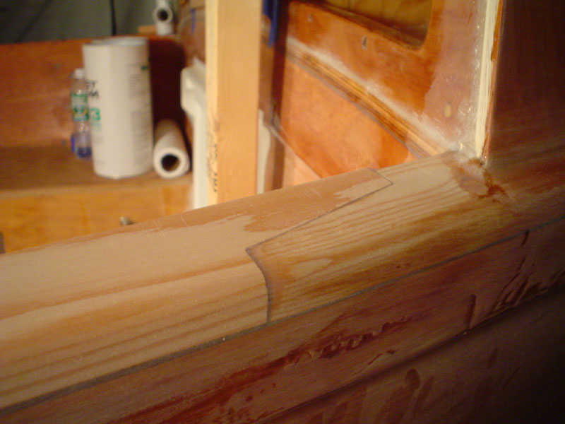Outside of rail beltsanded and shaped
Once laminated on, with only three clamps to pull it slightly down to the sheer, the outside edge is now belt sanded flush to the rubrail, given a rough curve to its top outboard edge, and then hand sanded with a block and 100 grit.  A piece of the console is seen on the cuddy top.
