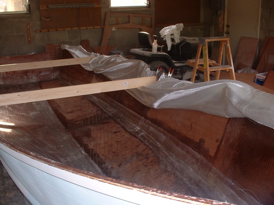 7/12/05   Then I lifted the cloth over the side and epoxied the hull bottom and a little up the sides....then I unclamped the cloth and layed it back over itself and epoxied the sides..allowed me to glass this large area without a helper.

